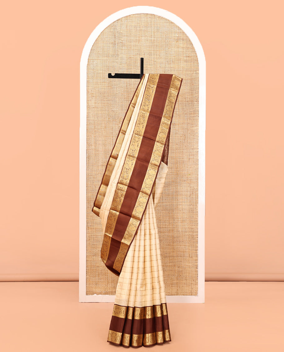 Cream Vasundhara Silk Saree, Enthralled with Zari Buttas Enclosed Checks All Over Its Body, Complemented by a Contrast Rettai Pettu Border of Muthu, Banaras, and Iruthalai Pakshi Designs, a Grand Pallu, and Paired with a Contrast Blouse