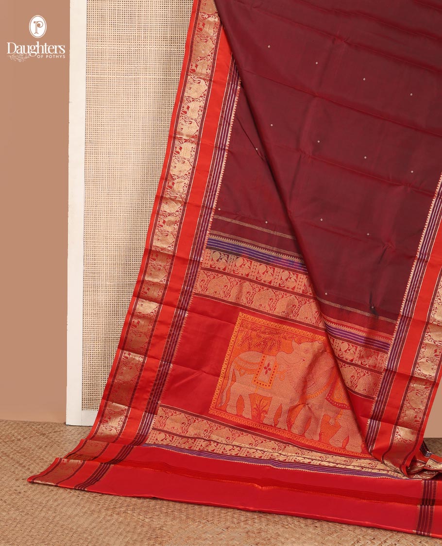 Maroon thread buttas Kanchipuram silk saree, contrast rettai pettu border of rekku, rudraksham, yaanai, and Pichwai cow designs, and pallu features Vrishabha Kunjara design