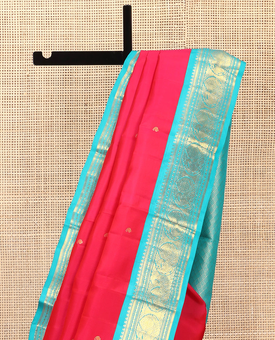 Red Vasundhara Silk Saree, Subtly Sparkled With Zari Buttas All Over Its Body, Complemented by Zari Buttas All Over Its Body, Complemented by Contrast Border of Thilakam, Banaras, and Mayil Designs Grand Jaal Pallu and Paired with a Contrast Blouse