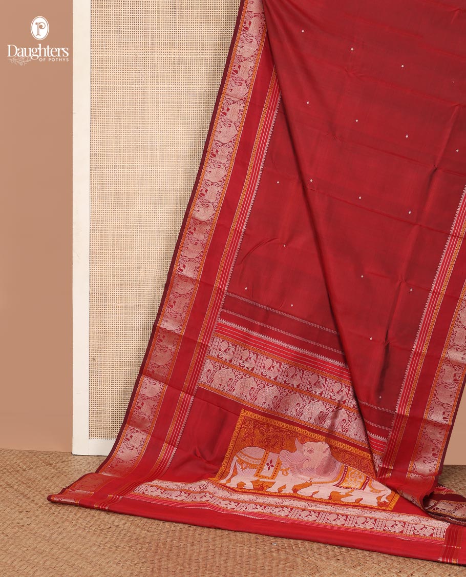 Red thread buttas Kanchipuram silk saree, rettai pettu border of rekku, rudraksham, yaanai, and Pichwai cow designs, and pallu features Vrishabha Kunjara design