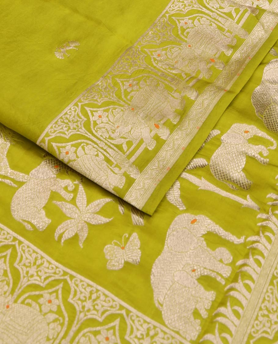 Parrot green zari buttas raw mango silk saree, Mughal border of elephant motifs, and pallu decked up with coconut tree, elephant, and butterflies