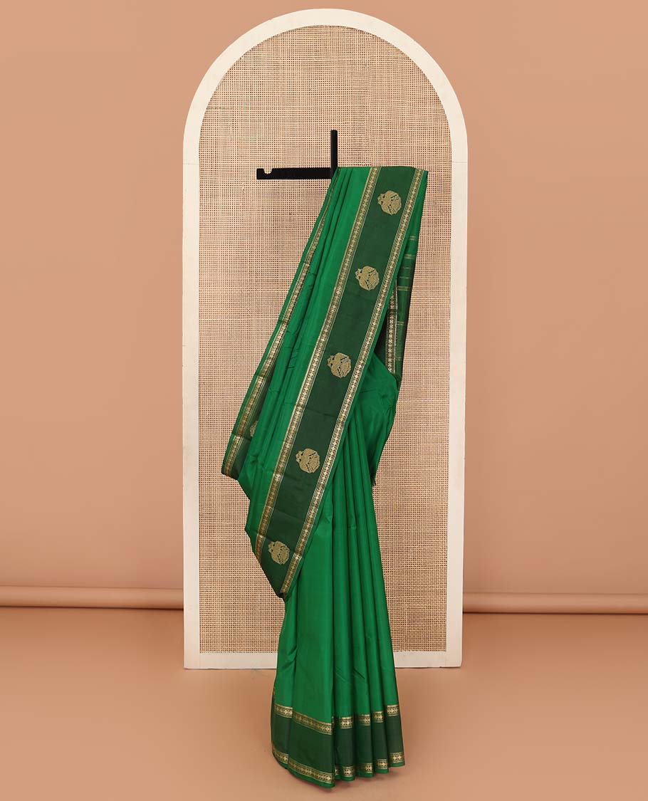 Green plain Kanchipuram silk saree, contrast border of rekku, muthu, rudraksham and iruthalai pakshi motifs, and zari striped pallu