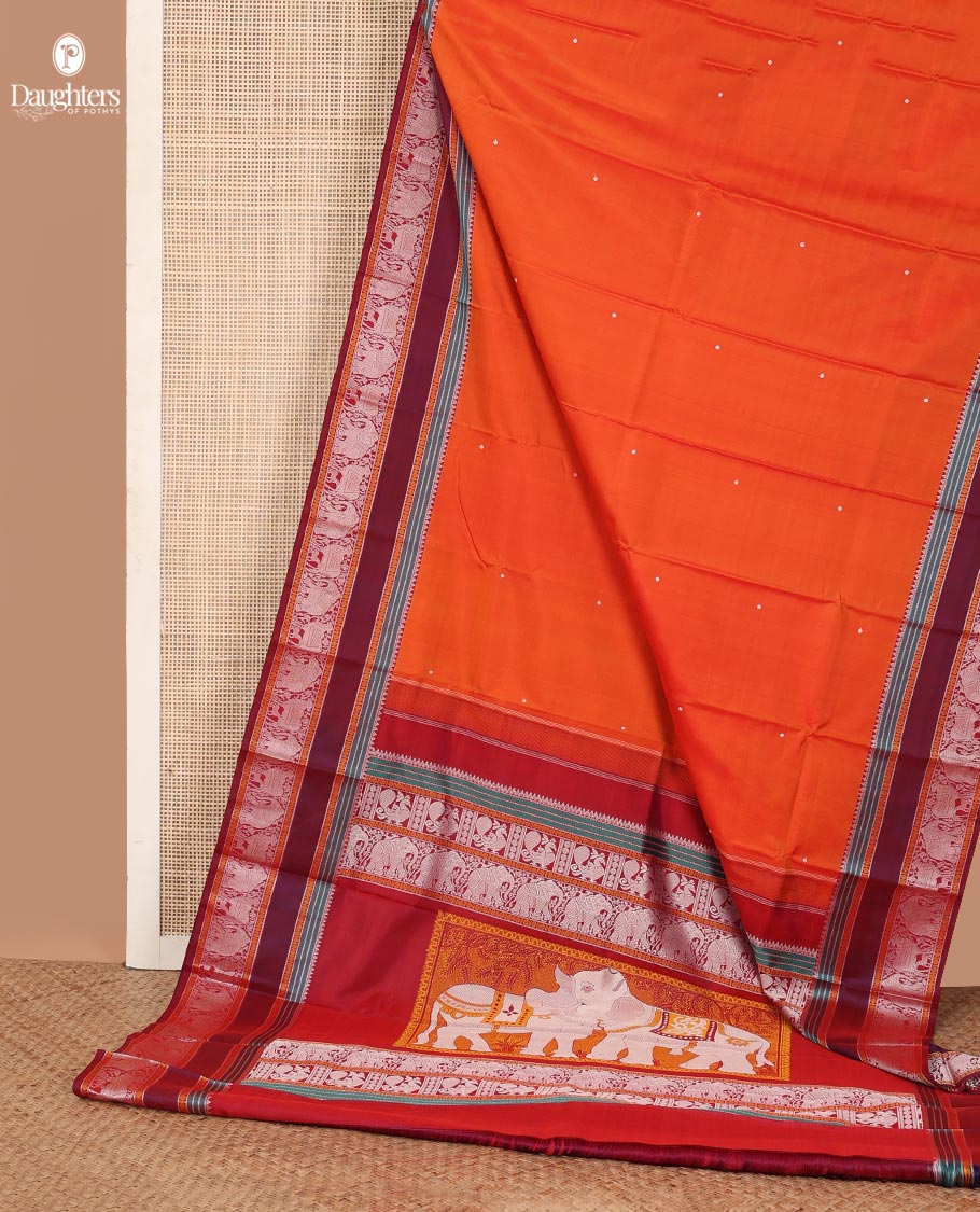 Orange thread buttas Kanchipuram silk saree, contrast rettai pettu border of rekku, rudraksham, yaanai, and Pichwai cow designs, and pallu features Vrishabha Kunjara design