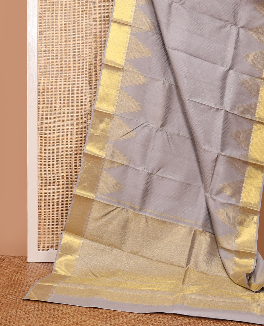 Grey embossed silk saree, thazampoo rekku golden zari border of thilakam mokku, muthu, and vanki designs, and zari rich jaal pallu