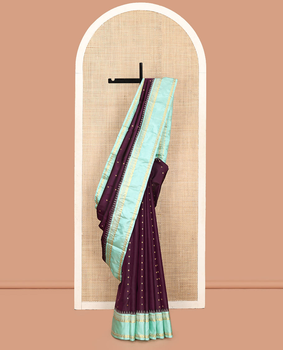Purple Vasundhara Silk Saree, Spotlighted With Zari Buttas All Across Its Body, Complemented by Captivating Contrast Rettai Pettu Border of Thazampoo Rekku, Muthu, And Manga Designs, a Gleaming Zari Design Pallu, And Paired With a Contrast Blouse