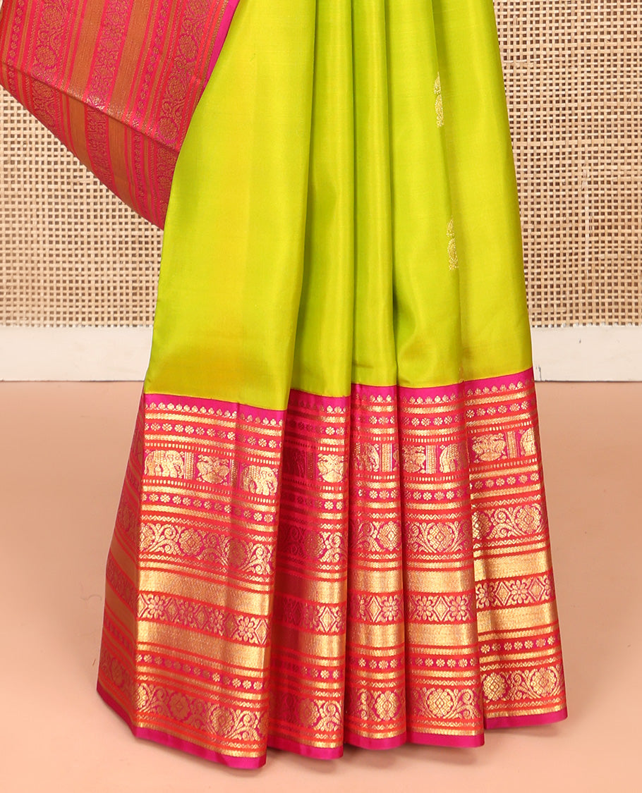 Green Vasundhara Silk Saree, Delicately Woven with Zari Buttas All Over Its Body, Complemented by Contrast Border of Thilakam Mokku, Kamalam, Iruthalai Pakshi, Yaanai, and Kamalam Designs, Vanki Design Pallu and Paired with a Contrast Blouse