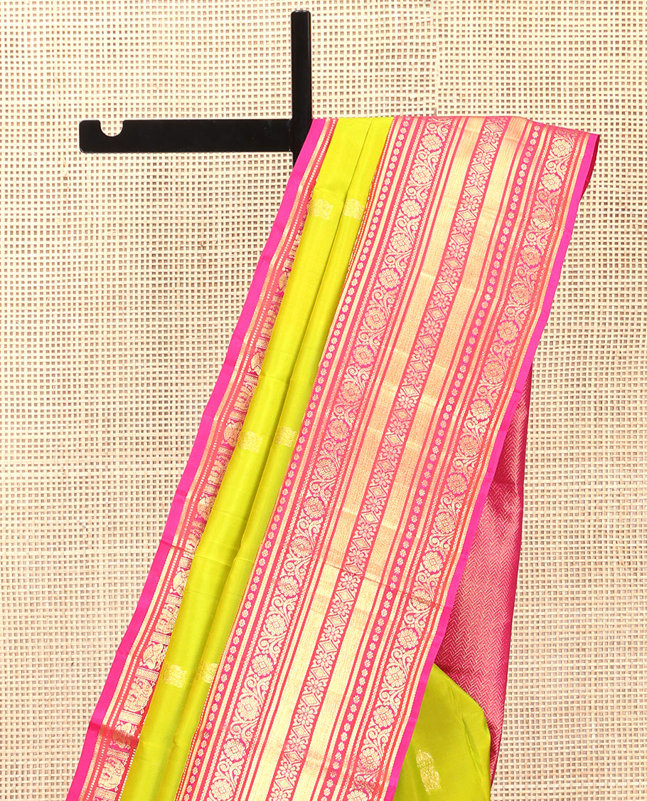 Green Vasundhara Silk Saree, Delicately Woven with Zari Buttas All Over Its Body, Complemented by Contrast Border of Thilakam Mokku, Kamalam, Iruthalai Pakshi, Yaanai, and Kamalam Designs, Vanki Design Pallu and Paired with a Contrast Blouse