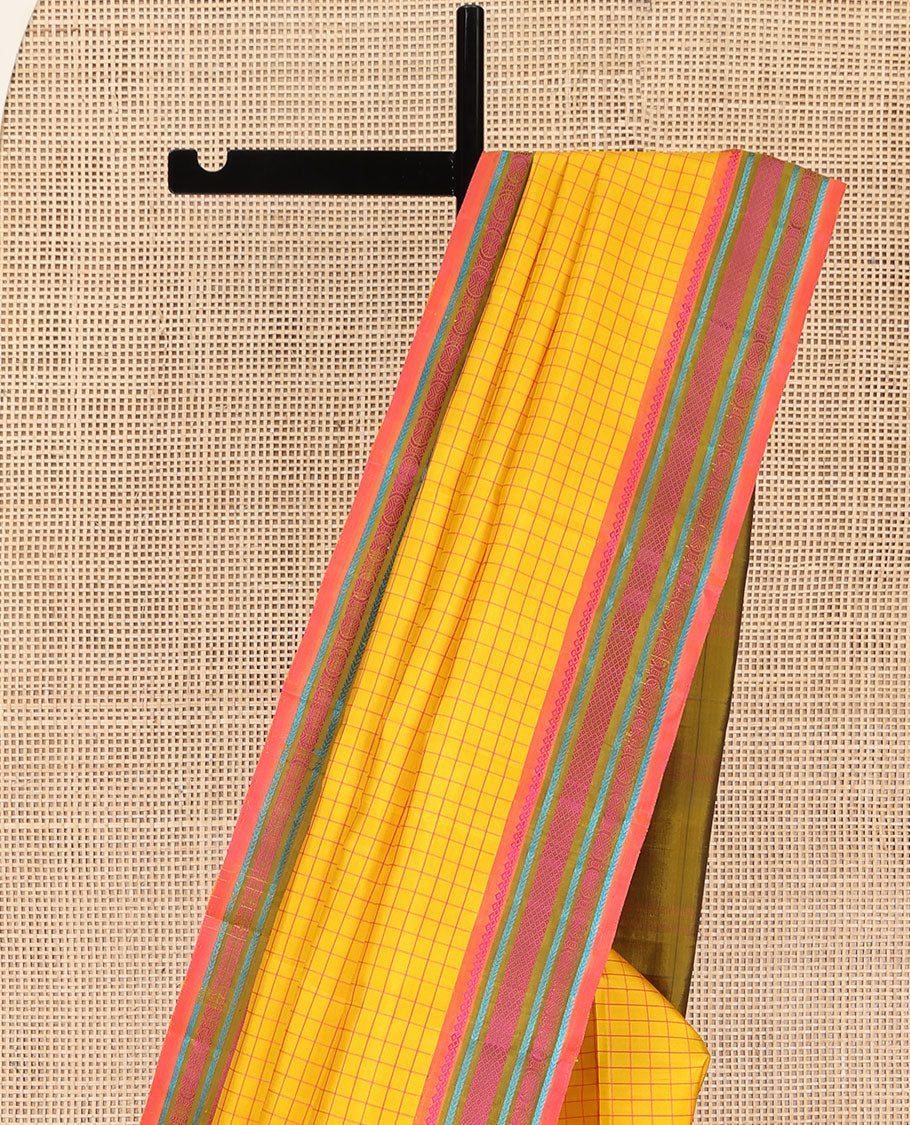 Yellow kanchipuram silk saree, subtly sparkled with checked design on its body, complemented by a contrast border of salngai, kathir, mayil kann, kathir, and rudraksham designs, a subtly striped pallu, and paired with a contrast blouse