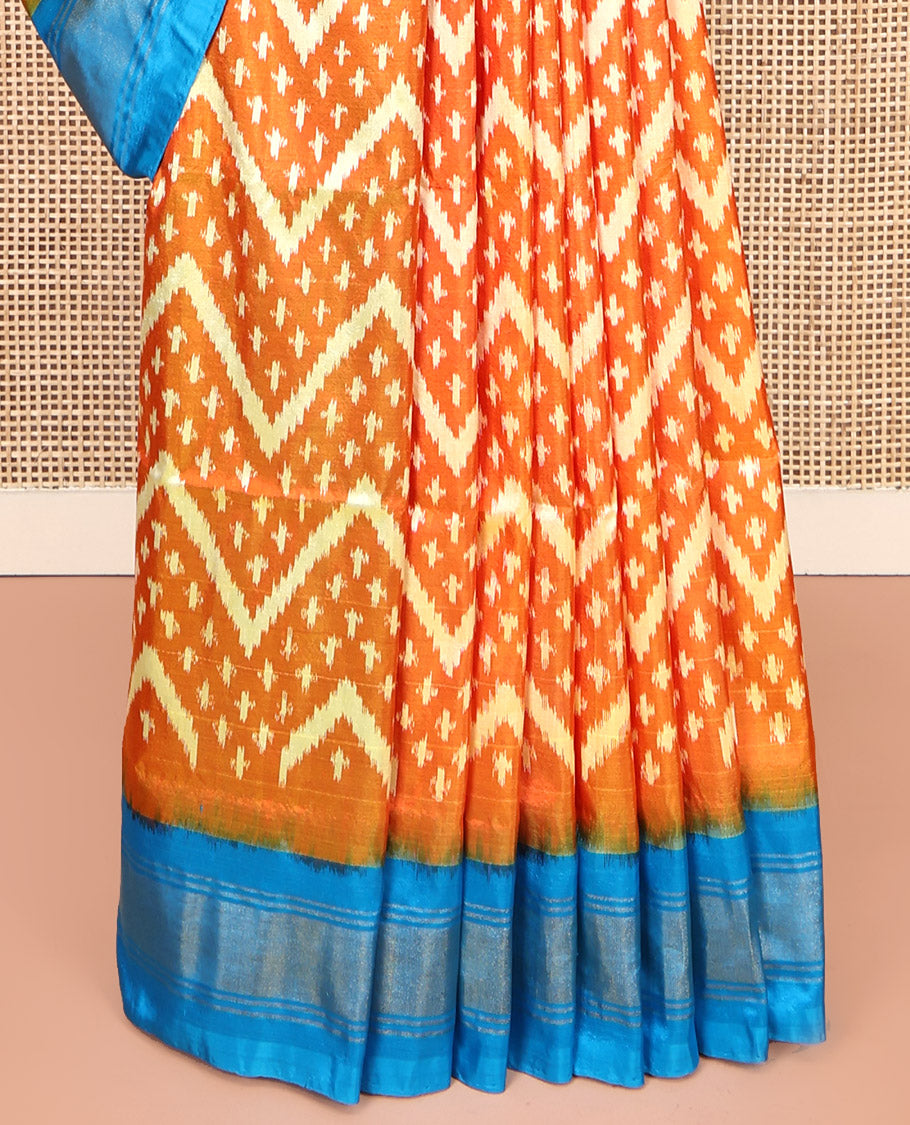 Orange Pochampally Ikat Silk Saree, Ornamented with Buttas and Chevron Design on Its Body, Complemented by a Contrast Border, Pallu of Jaal Designs in Ikkat Weave, and Paired with a Contrast Blouse