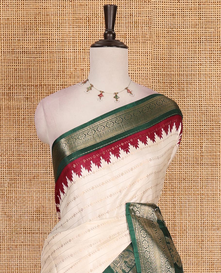 Half-white zari designs dola silk saree, contrast green temple traditional border of peacock and elephant motifs, and temple pallu