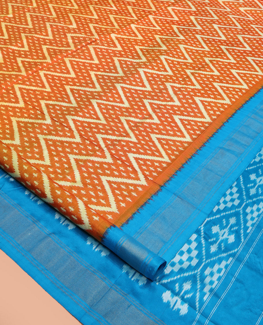 Orange Pochampally Ikat Silk Saree, Ornamented with Buttas and Chevron Design on Its Body, Complemented by a Contrast Border, Pallu of Jaal Designs in Ikkat Weave, and Paired with a Contrast Blouse