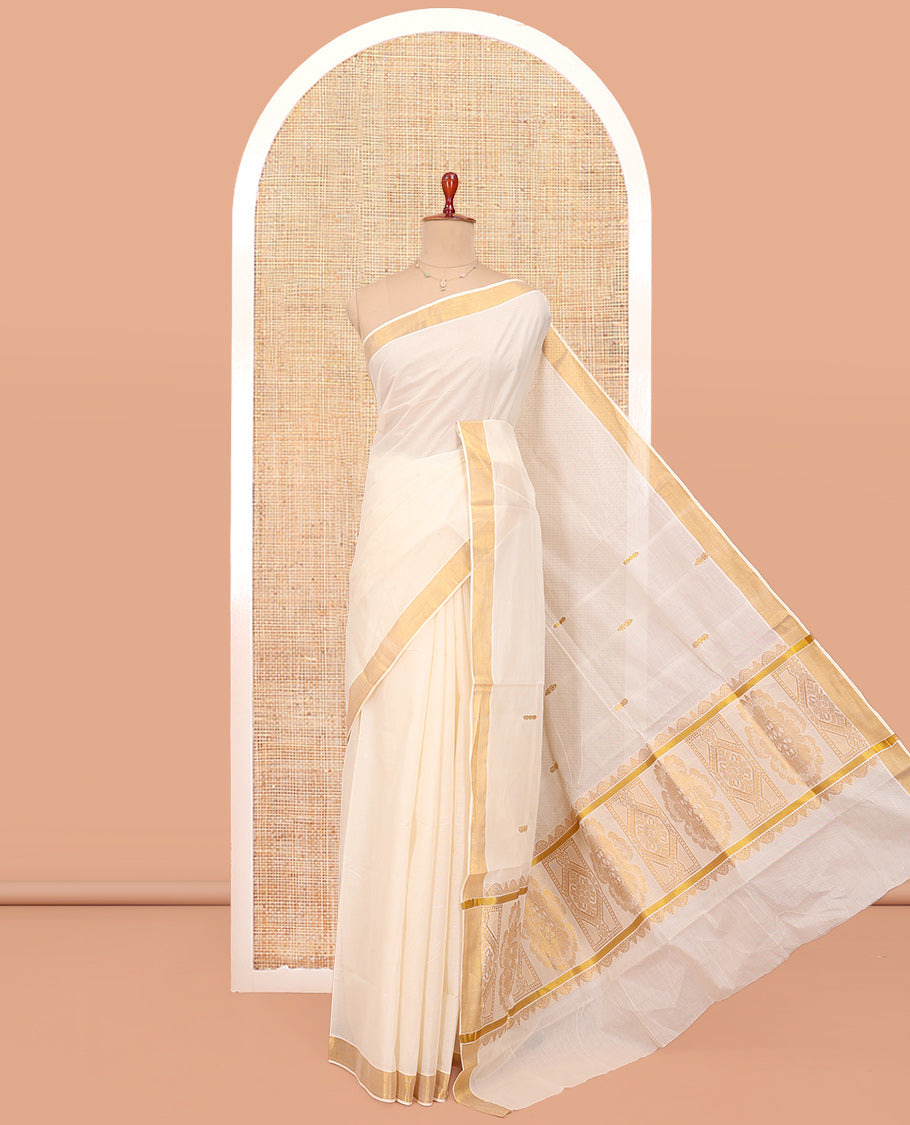 Cream Kerala Cotton Saree, Ornamented with Zari Buttas All Over Its Body, a Zari Bavanji Border, Pallu of Intricate Designs, and Paired with a Matching Blouse