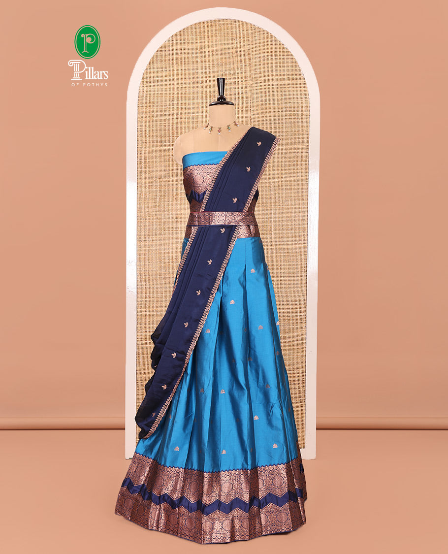 Light Blue and Navy Blue Semi-Banarasi Half-Saree Adorned with Zari Buttas on Its Skirt, Complemented by Contrast Traditional Zari Border of Chakram Designs, Paired with a Matching Blouse, and a Satin Georgette Embroidered Scallop Dhavani