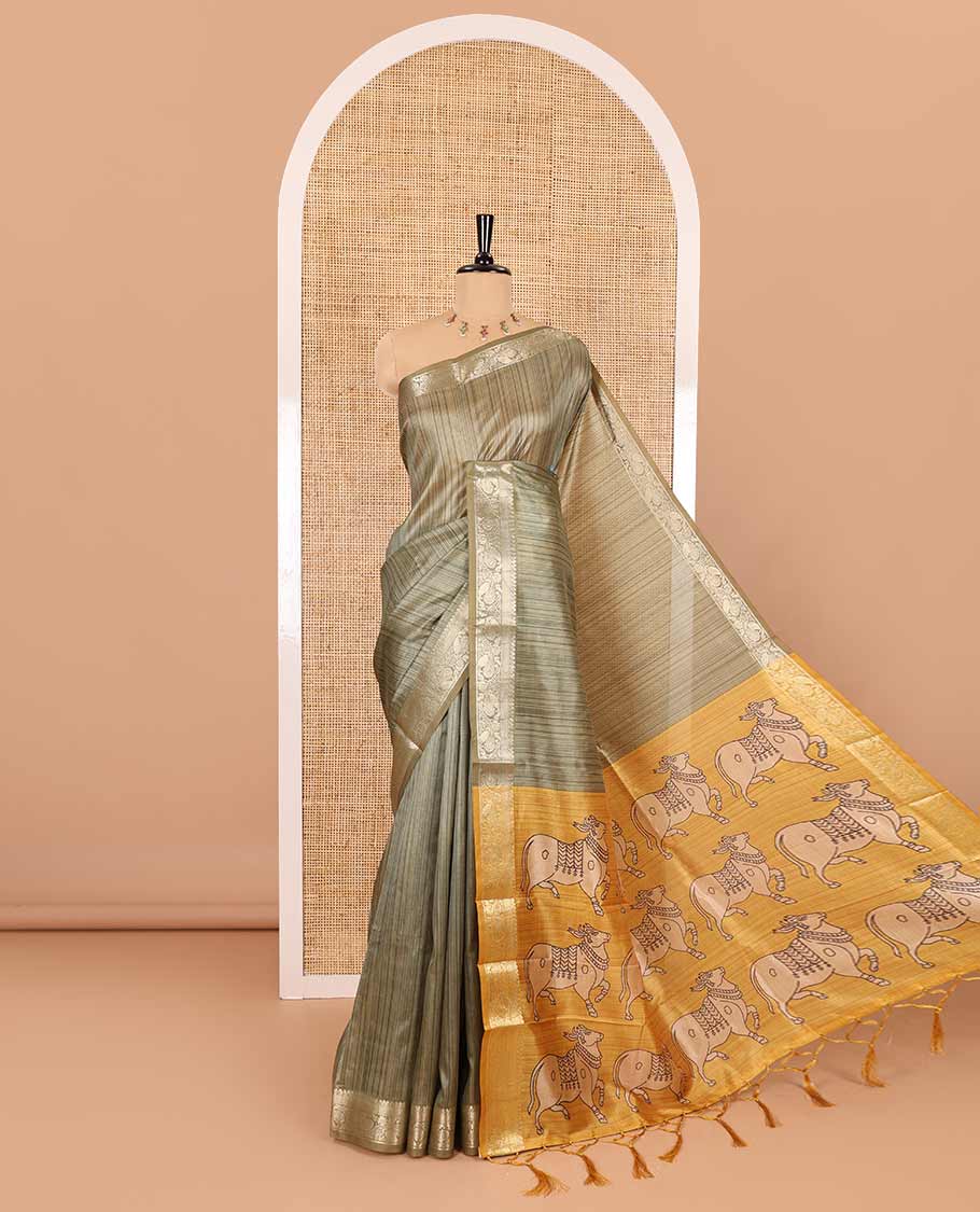 Olive green striped semi-tussar saree, traditional zari border of floral creeper designs, contrast pallu of Pichwai cow print, and contrast Pichwai cow printed blouse