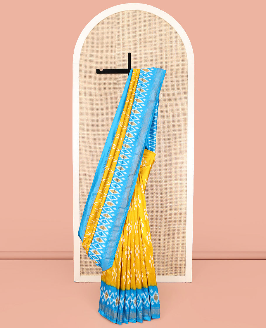 Mustard Ikkat Silk Saree, Masterfully Woven with Ikkat Buttas All Over Its Body, Complemented by a Contrast Diamond-Patterned Border, Pallu of Ikkat Butta Enclosed Checks, and Paired with a Contrast Blouse