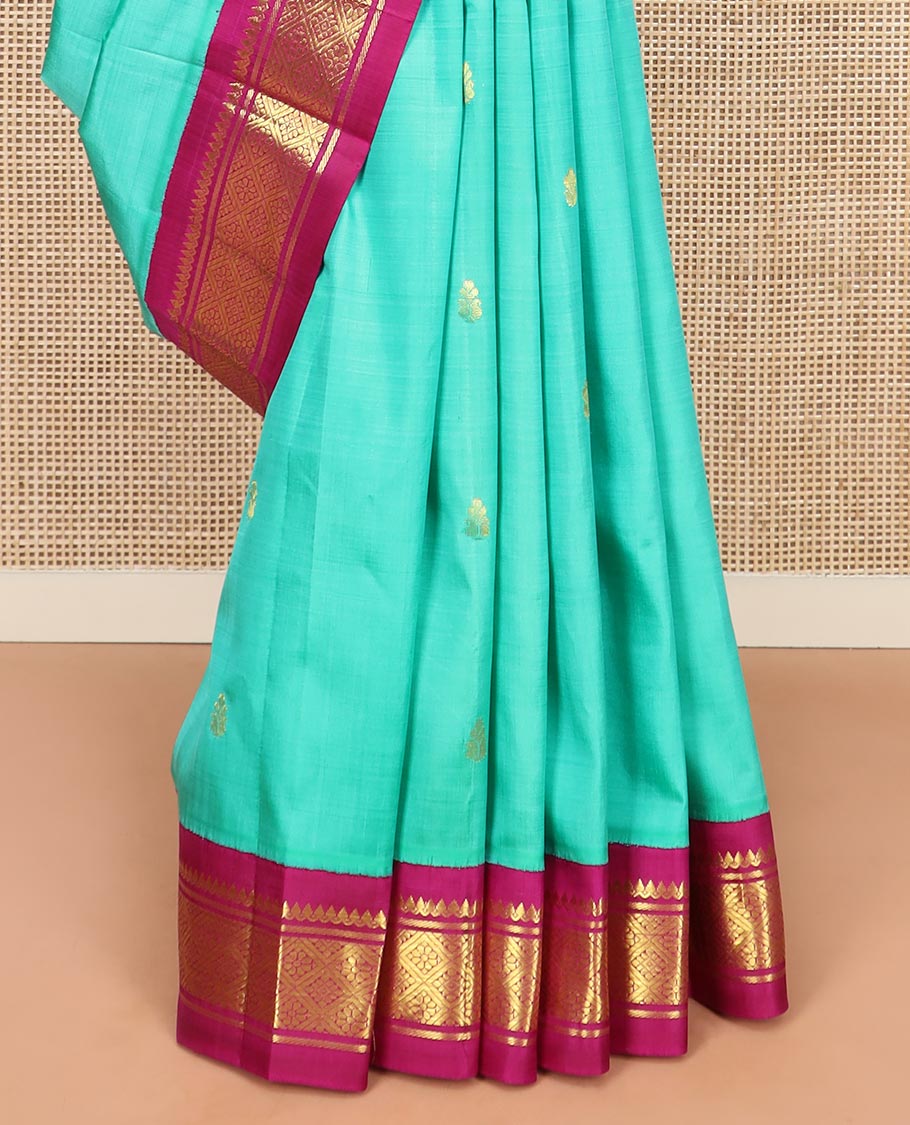 Turquoise Kanchipuram Silk Saree Bedecked with Zari Buttas All Over Its Body, Complemented by a Contrast One-Sided Korvai Border of Thilakam Mokku, Banaras, and Jaal Designs, Pallu of Zari Designs, and Comes Without a Blouse