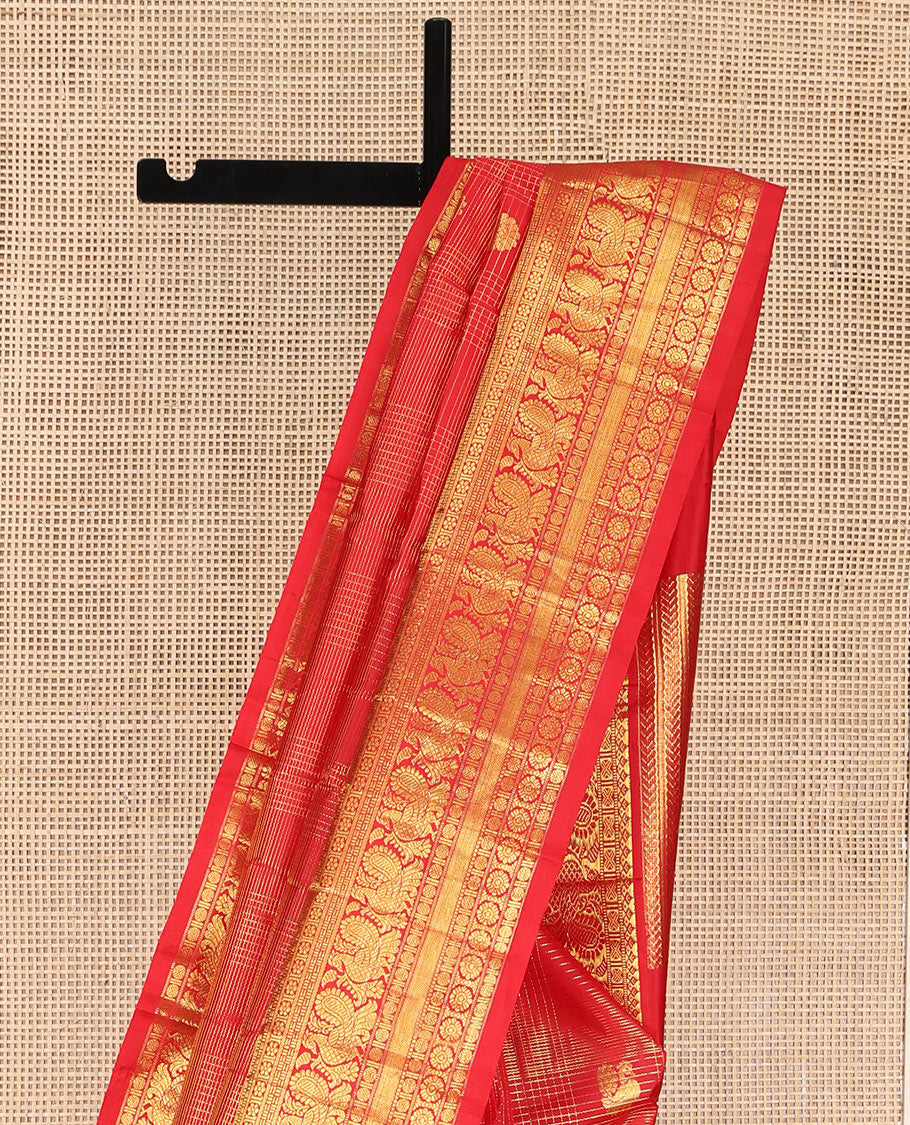 Red Kanchipuram Silk Saree, Gleamed Up with Mayil Butta Enclosed Checks, Highlighted by One-Sided Border of Thilakam Mokku, Kamalam, Mayil, Chakram, and Rudraksham Designs, Pallu of Chakram and Mayil Designs, and Comes Without a Blouse