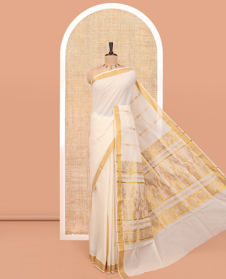 Cream Kerala Cotton Saree, Delicately Woven with Zari Stripes All Over Its Body, a Subtle Bavanji Border, Pallu Depicts Peacock Designs, and Paired with a Matching Blouse