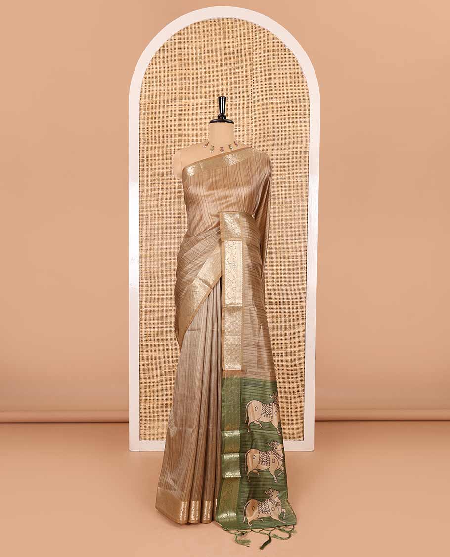 Chikku striped semi-tussar saree, traditional zari border of floral creeper designs, contrast pallu of Pichwai cow print, and contrast Pichwai cow printed blouse