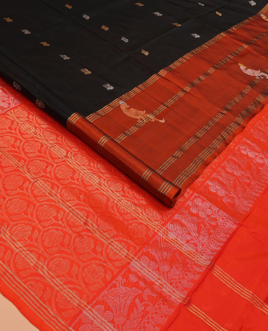 Inky Black Uppada Silk Saree Enlivened With Zari Buttas, Captivating Contrast Border Featuring Zari Stripes And Peacock Motifs, Pallu Depicting Rose Flower-Enclosed Mughal-Style Arches, And Paired With A Contrast Blouse
