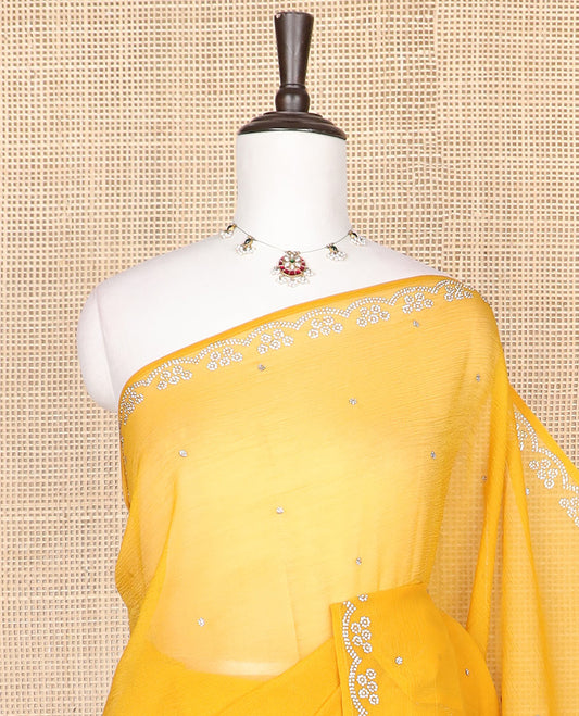 Yellow Swarovski stone embroidered designer saree with stones embedded in its body, a flower-shaped stone aligned scallop border