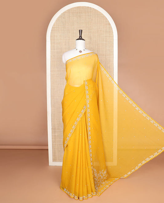 Yellow Swarovski stone embroidered designer saree with stones embedded in its body, a flower-shaped stone aligned scallop border