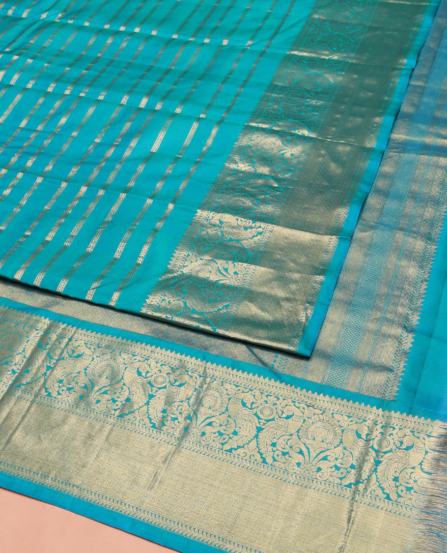 Blue Vasundhara Silk Saree, Gleamed Up with Muthu, and Neli Stripes, Complemented by a Zari Border of Thilakam, Kathir, Mayil, and Jaal Designs, Pallu Depicting Diagonal Stripes, and Paired with a Matching Blouse