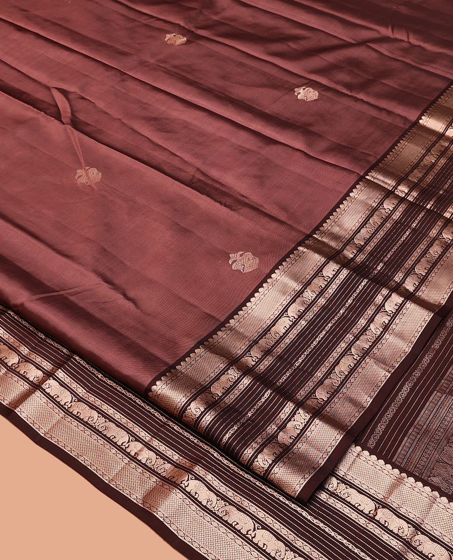Brown Vasundhara Silk Saree, Detailed with Iruthakshi Buttas All Over Its Body, Complemented by a Contrast Border of Thilakam Mokku, Vanki, Yaanai, and Muthu Designs, Grand Pallu, and Paired with a Contrast Blouse