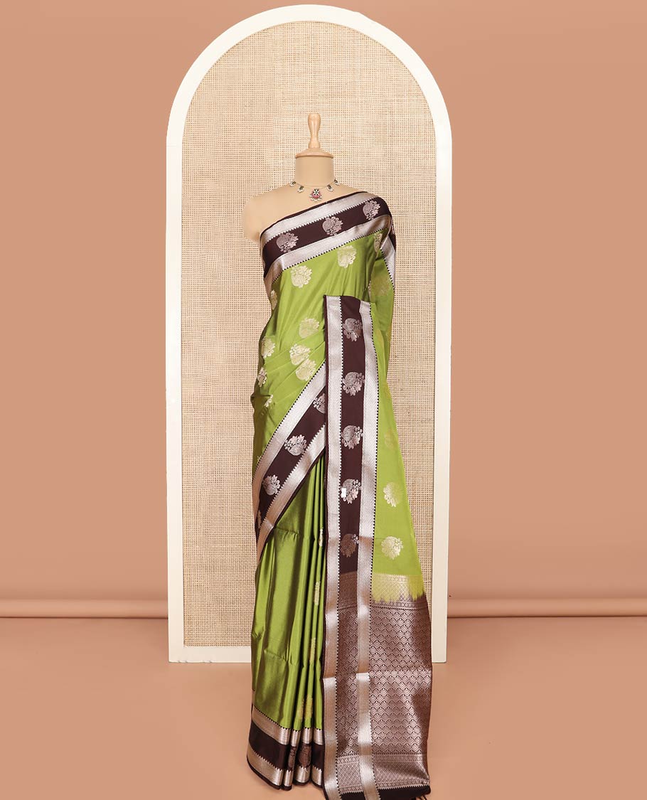 Green Semi-Soft Silk Saree Enriched with Floral Zari Buttas, Complemented by Contrast Traditional Zari Border Featuring Floral and Peacock Feather Motifs, Pallu Intricately Designed with Jaal Designs, and Paired with a Contrast Blouse