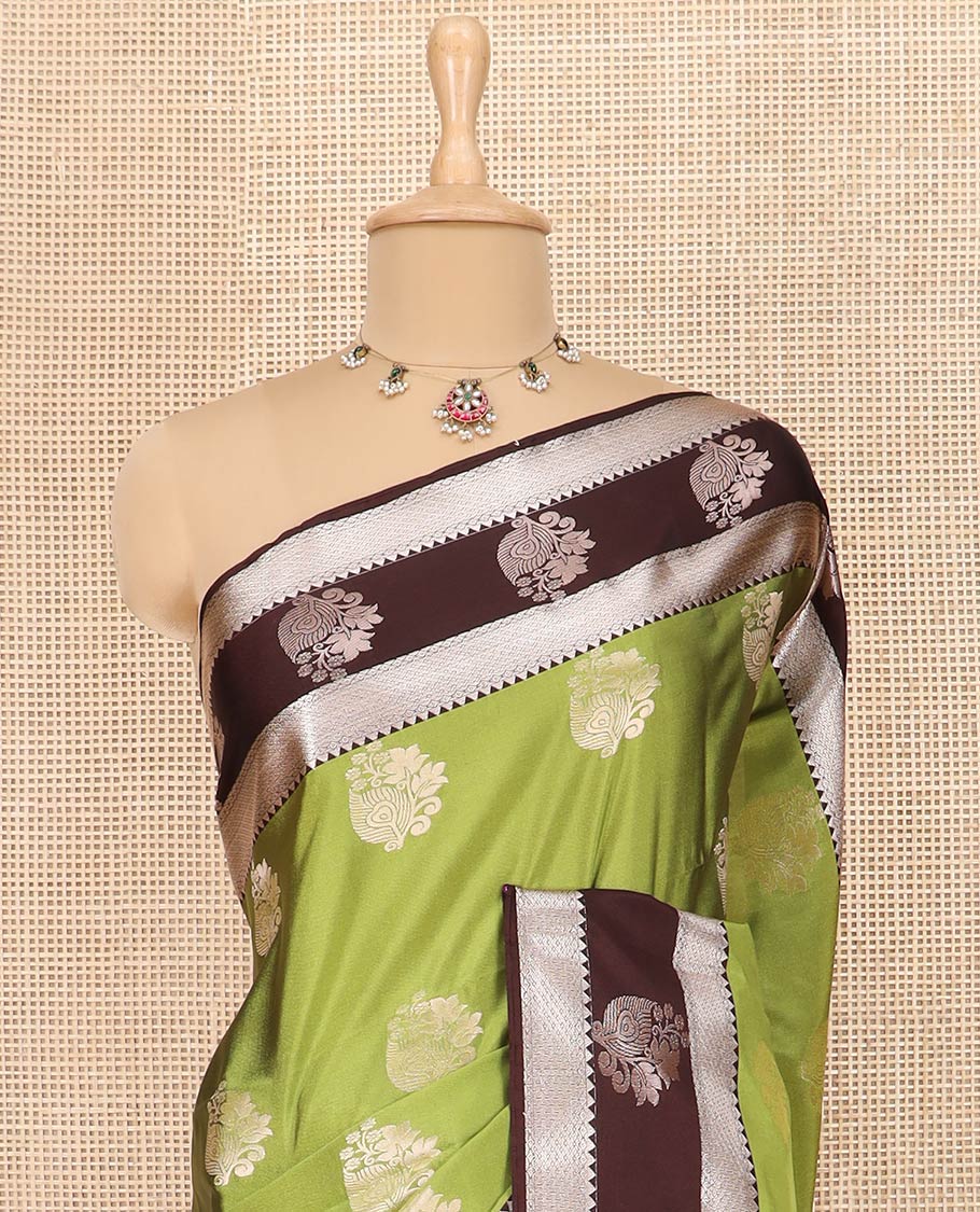 Green Semi-Soft Silk Saree Enriched with Floral Zari Buttas, Complemented by Contrast Traditional Zari Border Featuring Floral and Peacock Feather Motifs, Pallu Intricately Designed with Jaal Designs, and Paired with a Contrast Blouse