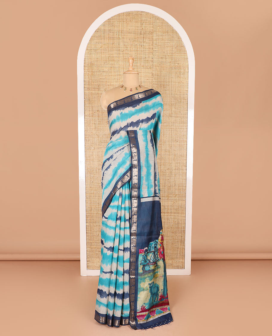 Blue shibori printed muslin cotton saree, contrast peacock zari border, village scenery printed pallu, and a contrast polka dotted zari border blouse