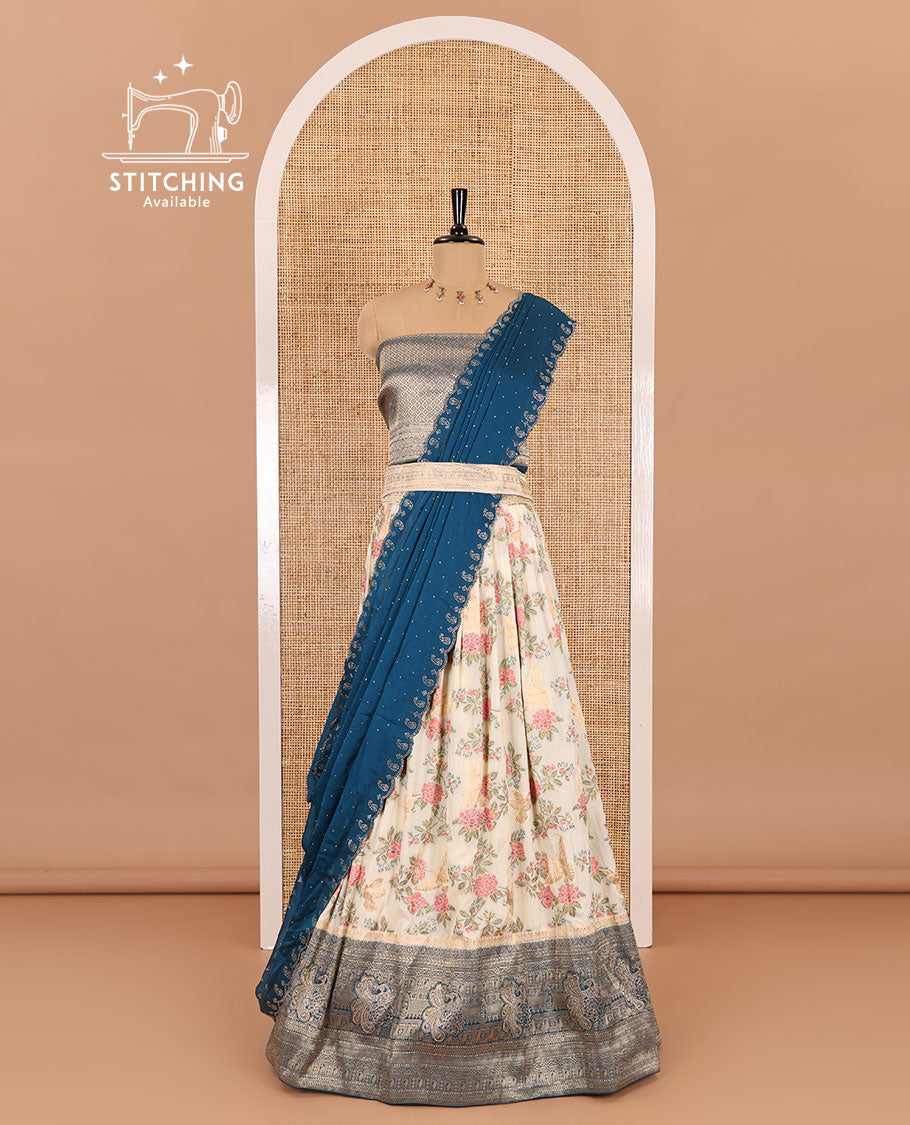 Cream and peacock blue half-saree, floral and bird printed nylon viscose crepe top, contrast traditional zari and stone work border, jacquard banaras blouse, and scallop stone work dhavani