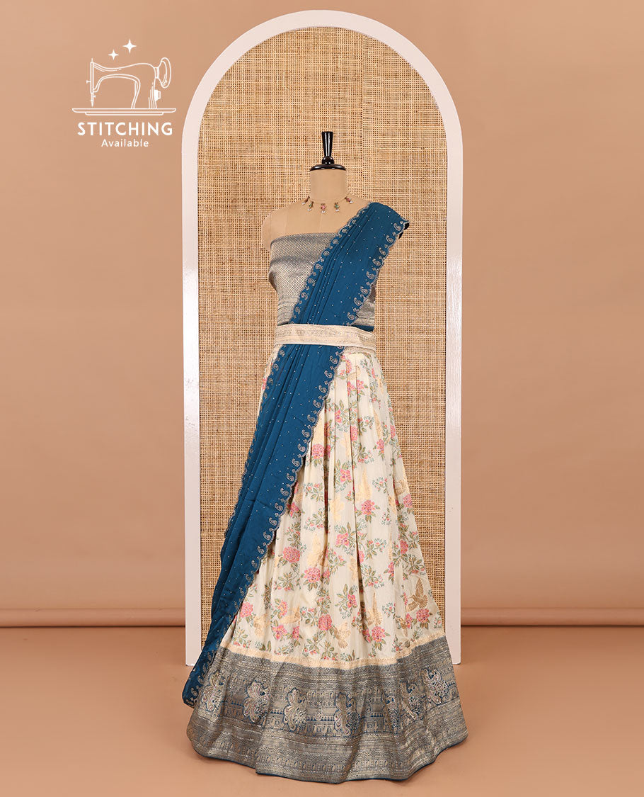 Cream and peacock blue half-saree, floral and bird printed nylon viscose crepe top, contrast traditional zari and stone work border, jacquard banaras blouse, and scallop stone work dhavani