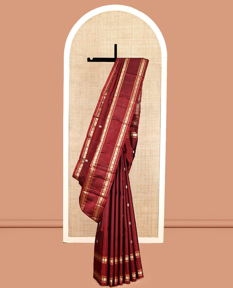 Maroon Kanchipuram Silk Saree, Adorned with Chakram Buttas, Highlighted by a Rettai Pettu Zari Border of Muthu, Banaras, and Cross Kamalam Designs, Mayil-Chakram Pallu and a Matching Blouse