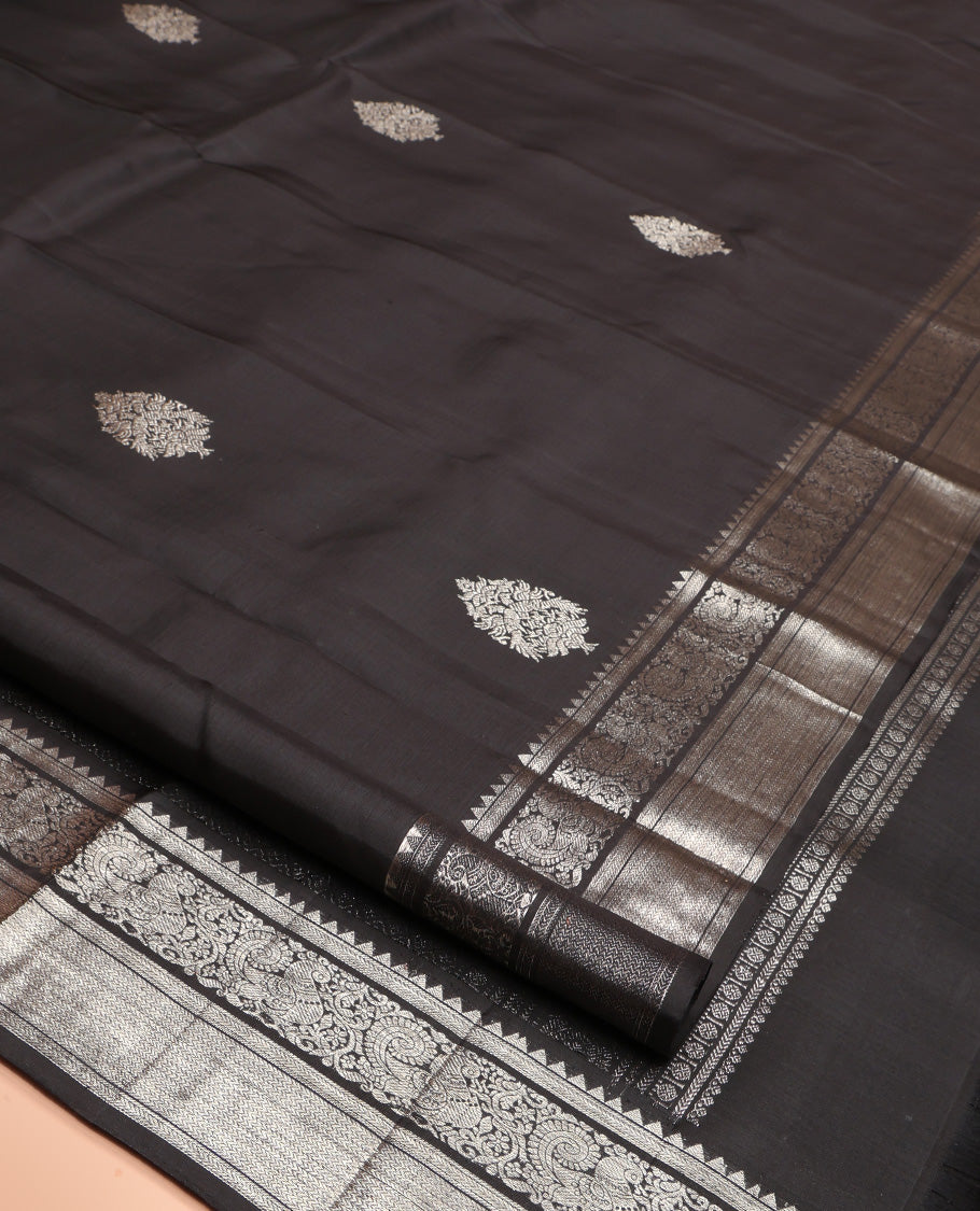 Black Kanchipuram Silk Saree, Dazzled with Zari Buttas All Over Its Body, Highlighted by Zari Border of Rekku, Kathir, Vanki, and Mayil Designs, Pallu of Jaal Design, and Paired with a Matching Blouse