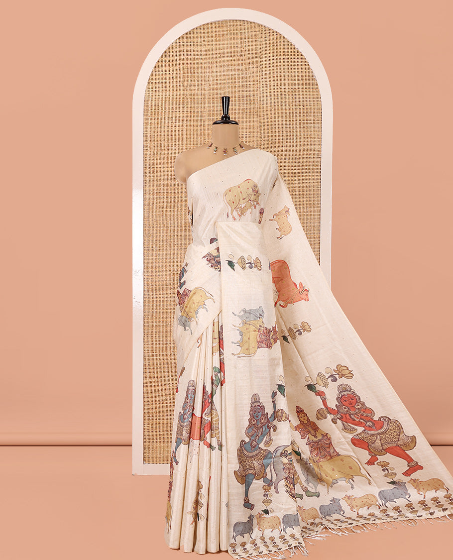 Borderless Cream Semi-Tussar Saree, Artfully Printed with Ancient Human Figurines, Floral, and Pichwai Cow on Its Body, Highlighted by Kalamkari-Style Human Motifs Printed Pallu, and Paired with a Matching Pichwai Cow Printed Blouse