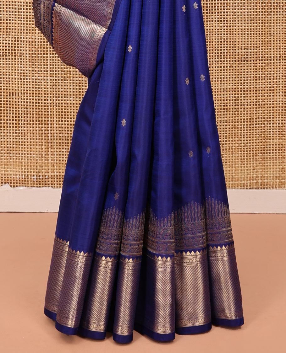 Blue Vasundhara Silk Saree Gleamed with Zari Buttas All Over Its Body, Highlighted with a Zari Border of Thilakam Mokku, Muthu, Cross Kamalam, and Mayil Kann Designs, Grand Pallu of Jaal Design, and Paired with a Matching Blouse