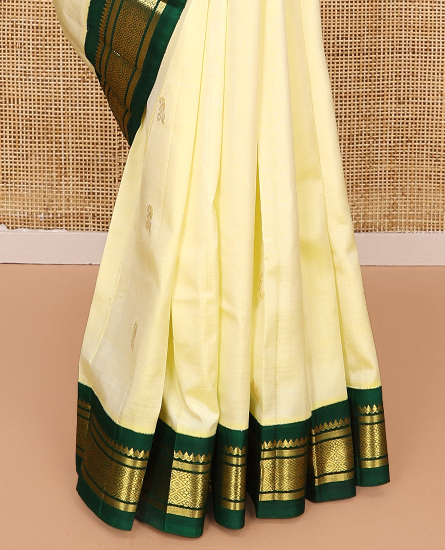 Pale Yellow Kanchipuram Silk Saree, Subtly Sparkled with Zari Buttas All Over Its Body, Complemented by a Contrast One-Sided Korvai Border of Thilakam Mokku, Banaras, and Jaal Designs, Pallu of Zari Designs, and Comes Without a Blouse