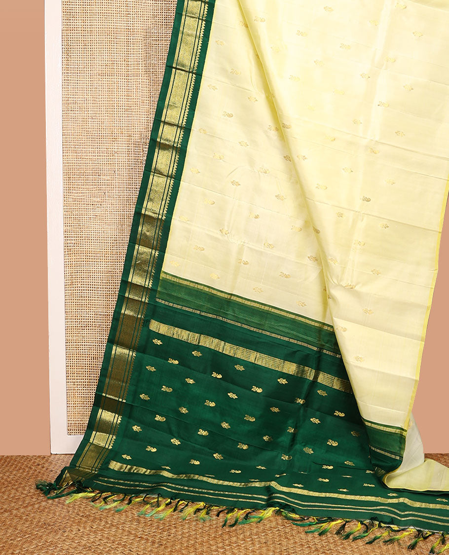Pale Yellow Kanchipuram Silk Saree, Subtly Sparkled with Zari Buttas All Over Its Body, Complemented by a Contrast One-Sided Korvai Border of Thilakam Mokku, Banaras, and Jaal Designs, Pallu of Zari Designs, and Comes Without a Blouse