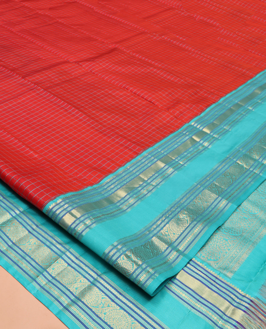 Tomato Red and Blue Vasundhara Silk Saree, Subtly Sparkled With Pattu Nool Kattam On Its Body, Complemented by Contrast Rettai Pettu Border of Salngai, Muthu, Neli, Rudraksham, and Dhavana Kodi Designs, Grand Pallu and Paired with a Contrast Blouse