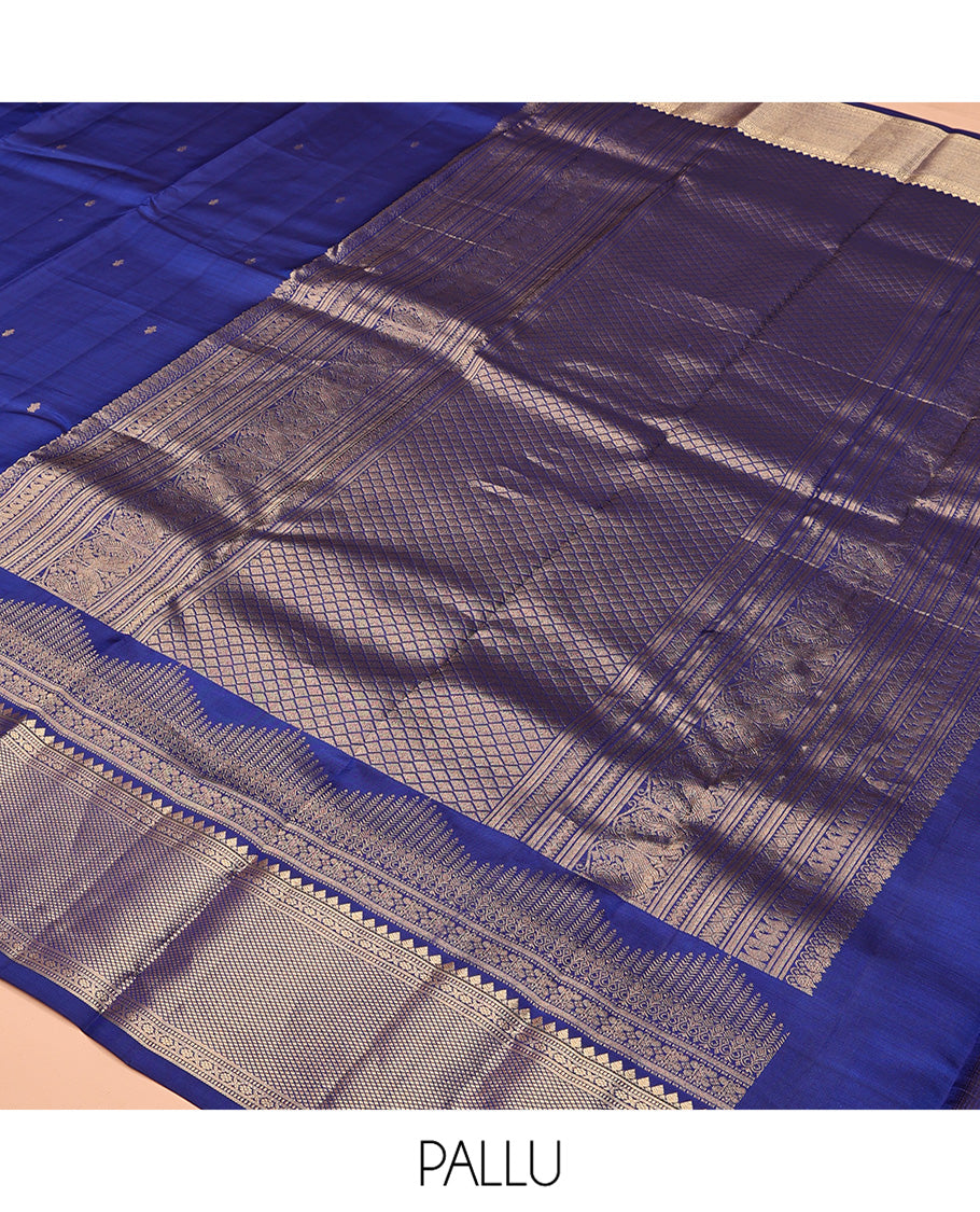 Blue Vasundhara Silk Saree Gleamed with Zari Buttas All Over Its Body, Highlighted with a Zari Border of Thilakam Mokku, Muthu, Cross Kamalam, and Mayil Kann Designs, Grand Pallu of Jaal Design, and Paired with a Matching Blouse
