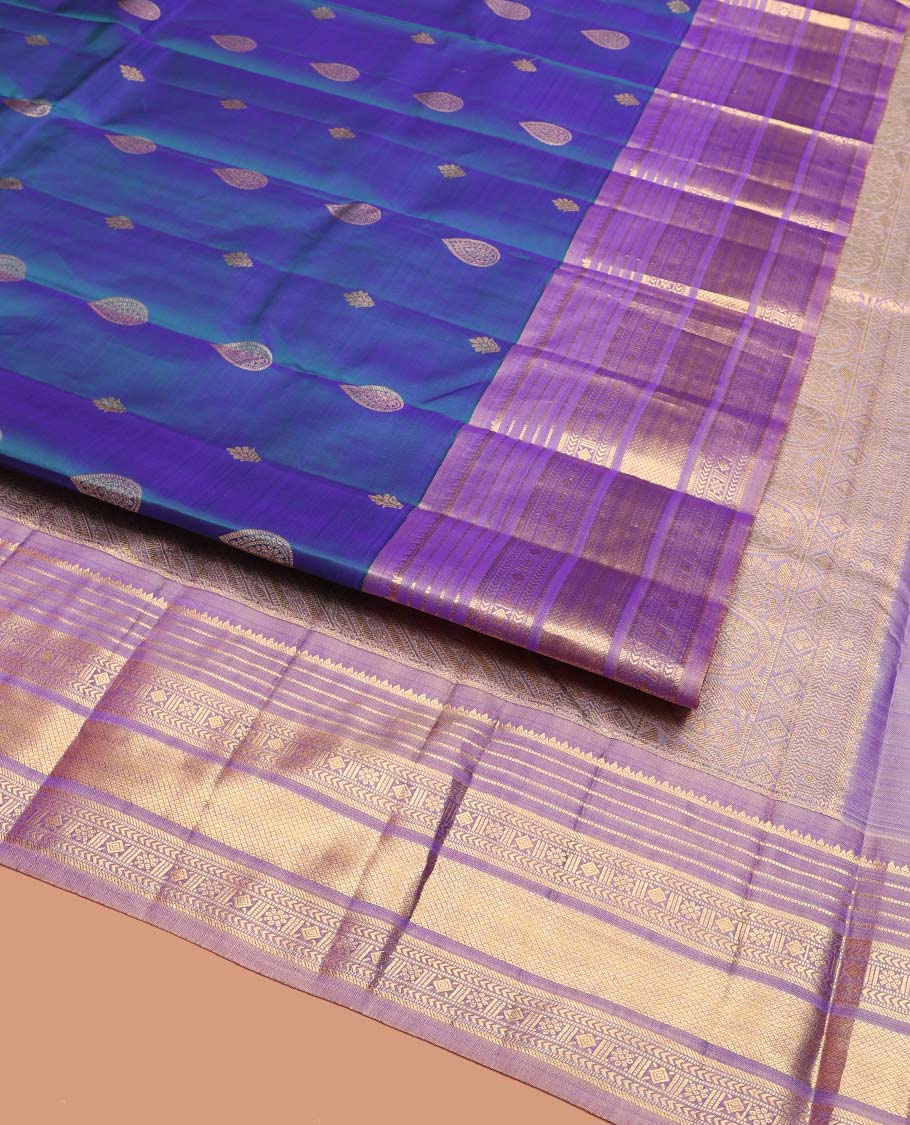 Blue Vasundhara Silk Saree, Adorned with Thilakam and Floral Buttas on Its Body, Complemented by a Contrast Border of Rekku, Muthu, Kathir, Kamalam, Diamond, and Mayil Kann Designs, Pallu Steeped with Intricate Designs, and Paired with a Contrast Blouse