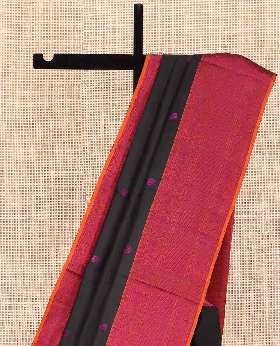 Black Kanchipuram Silk Saree, Masterfully Woven with Mayil-Chakram Buttas All Over Its Body, Complemented by a Contrast Border of Thilakam Mokku, Iruthalai Pakshi, and Kuyil Kann Designs, and Pallu of Jaal Designs, and Paired with a Contrast Blouse