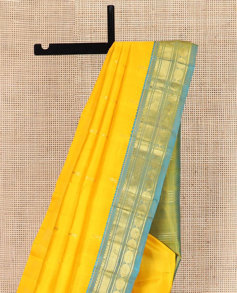 Yellow Kanchipuram Silk Saree Subtly Sparkled with Zari Buttas All Over Its Body, Complemented by a Contrast One-Sided Border of Thilakam Mokku, Banaras, Vanki, and Rudraksham Designs, Pallu of Zari Motifs, and Comes Without a Blouse