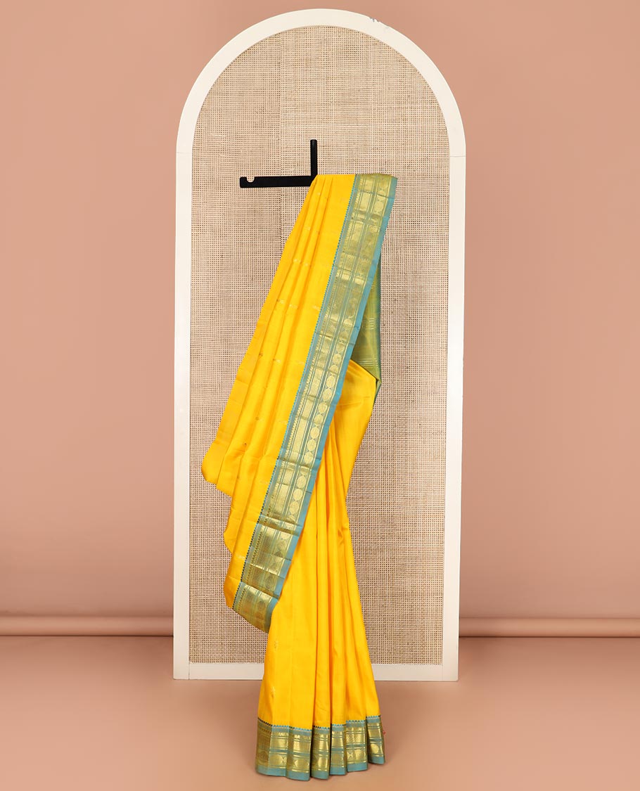 Yellow Kanchipuram Silk Saree Subtly Sparkled with Zari Buttas All Over Its Body, Complemented by a Contrast One-Sided Border of Thilakam Mokku, Banaras, Vanki, and Rudraksham Designs, Pallu of Zari Motifs, and Comes Without a Blouse
