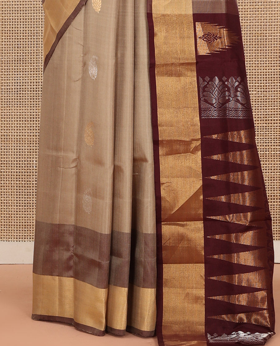 Light Sandal Uppada Silk Saree Highlighted with Paisley Buttas All Over Its Body, Complemented by Contrast Border of Temple and Chariot Designs, Grandly Woven Pallu of Temple Floral Vine Designs, and Paired with a Contrast Blouse