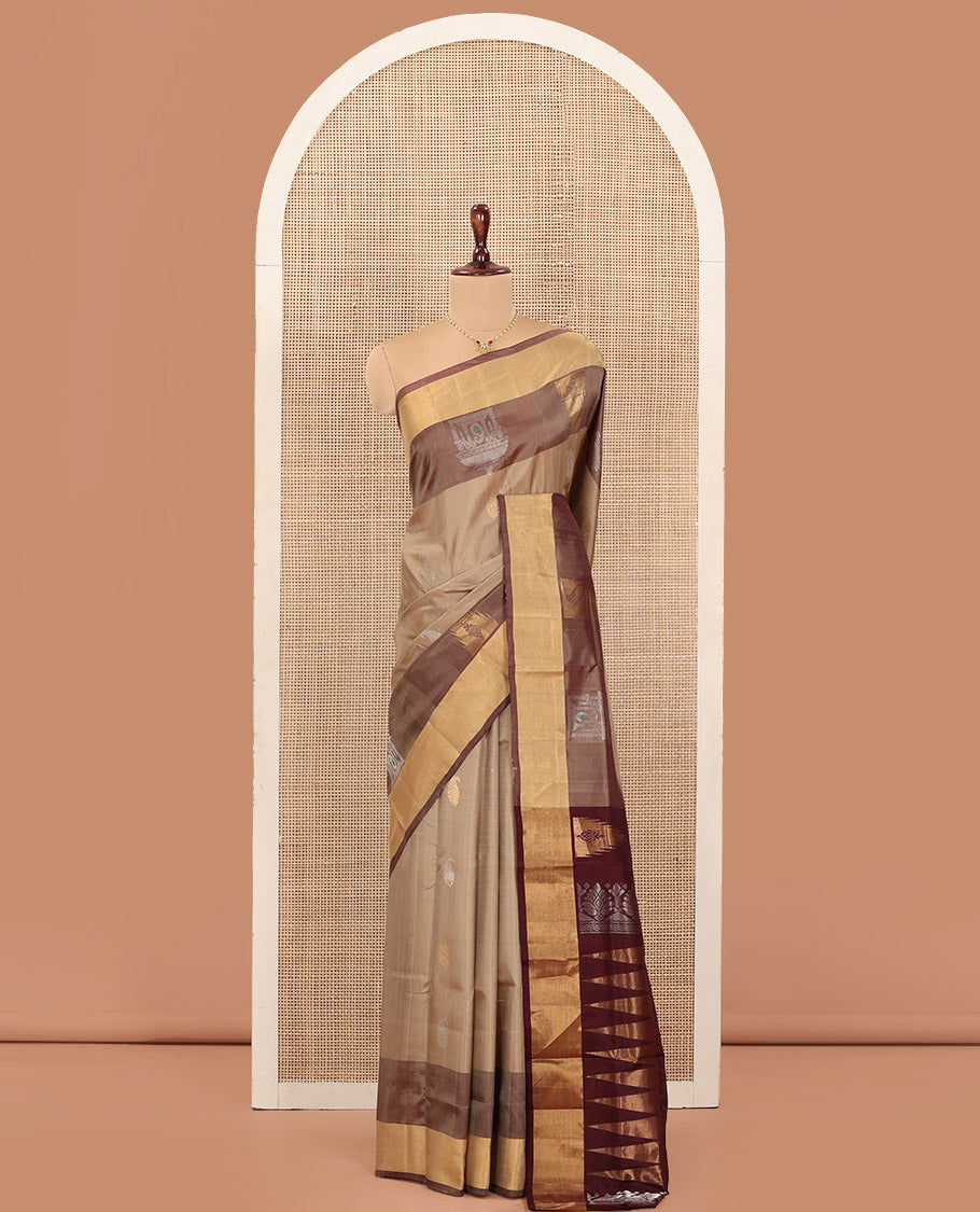Light Sandal Uppada Silk Saree Highlighted with Paisley Buttas All Over Its Body, Complemented by Contrast Border of Temple and Chariot Designs, Grandly Woven Pallu of Temple Floral Vine Designs, and Paired with a Contrast Blouse