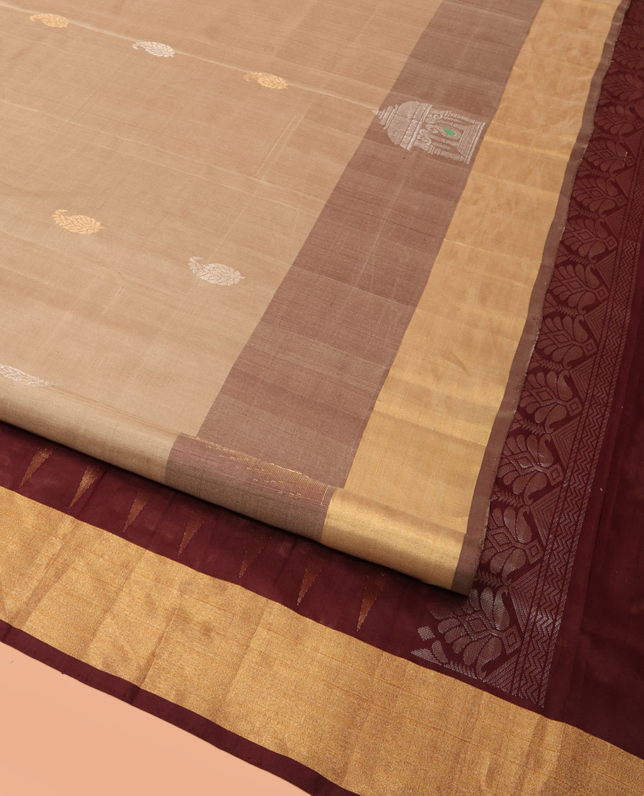Light Sandal Uppada Silk Saree Highlighted with Paisley Buttas All Over Its Body, Complemented by Contrast Border of Temple and Chariot Designs, Grandly Woven Pallu of Temple Floral Vine Designs, and Paired with a Contrast Blouse