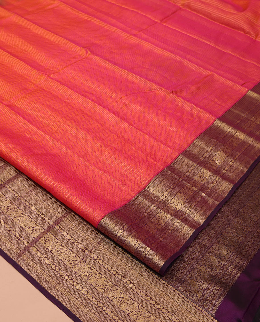 Orange Vasundhara Silk Saree, Gleamed Up with Stripes All Over Its Body, Complemented by a Contrast Border of Thilakam Mokku, Kathir, Vanki, Laddu Kamalam, and Mayil Designs, Intricately Designed Pallu, and Paired with a Contrast Blouse