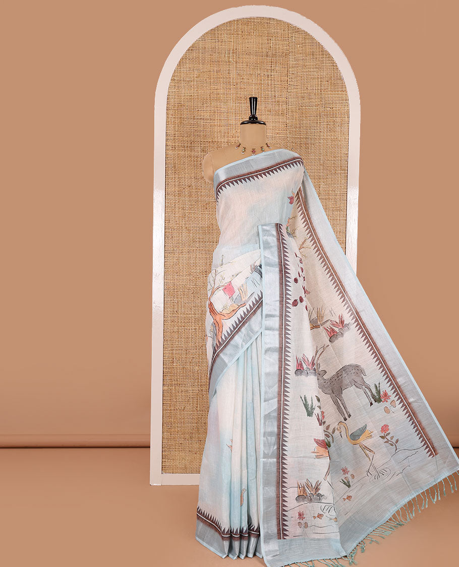 Sky blue nature-theme printed linen cotton saree features flora-fauna motifs, temple bavanji border, nature printed pallu, and a floral motif printed blouse